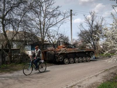 Велосипедист едет мимо остатков военной техники в селе Русанов Киевской области, где шли активные бои. Фото: Vladyslav Musiienko / Reuters