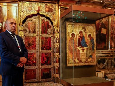Охранник стоит у иконы Троицы в соборе в Сергиевом Посаде, июль 2022. Фото: Maxim Shemetov / Reuters